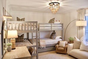 A hotel room with bunk beds, a sofa, a table, and a lamp.