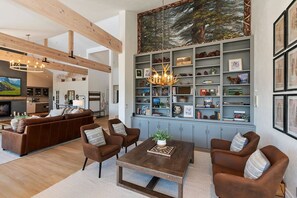 A spacious living room with a large bookshelf, a fireplace, and a dining area.