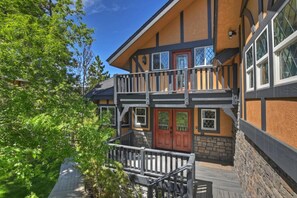 A two-story building with a balcony, wooden railings, and a stone foundation.