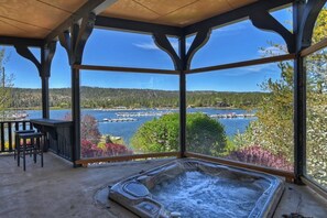 A hot tub in a covered outdoor area with a view of a lake and docked boats.