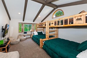 Une chambre avec des lits superposés, un bureau, des fauteuils en forme de poire et une fenêtre donnant sur un paysage verdoyant.