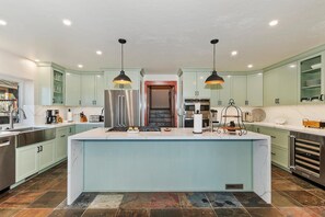 Una cocina moderna con una isla central, electrodomésticos de acero inoxidable e iluminación colgante.