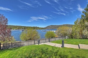 A waterfront property with a grassy lawn, a wooden fence, and a clear view of the water.