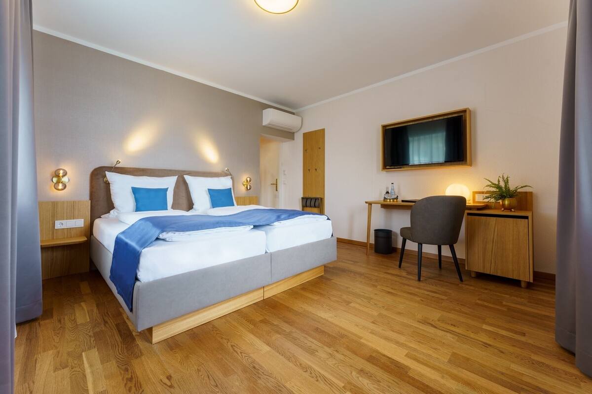 Una habitación de hotel moderna con una cama grande, un escritorio y un televisor.