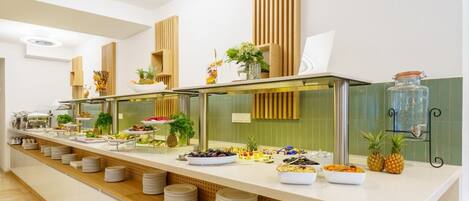 A buffet setup with various food items and a decorative plant.