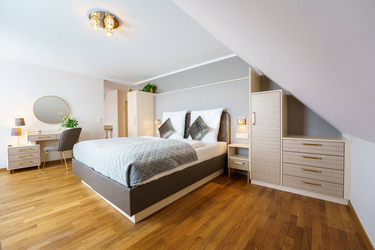 Un dormitorio moderno con cama, mesitas de noche, escritorio y armario.