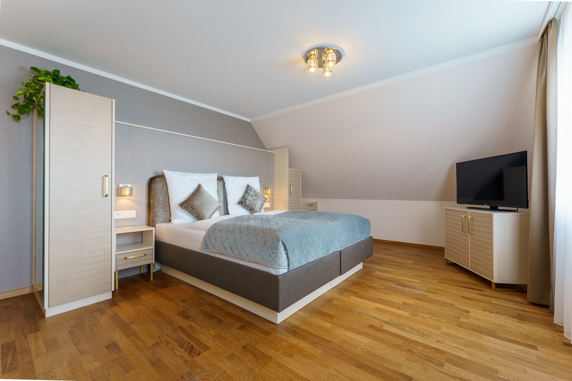 A modern bedroom with a bed, bedside tables, a TV, and a wardrobe.