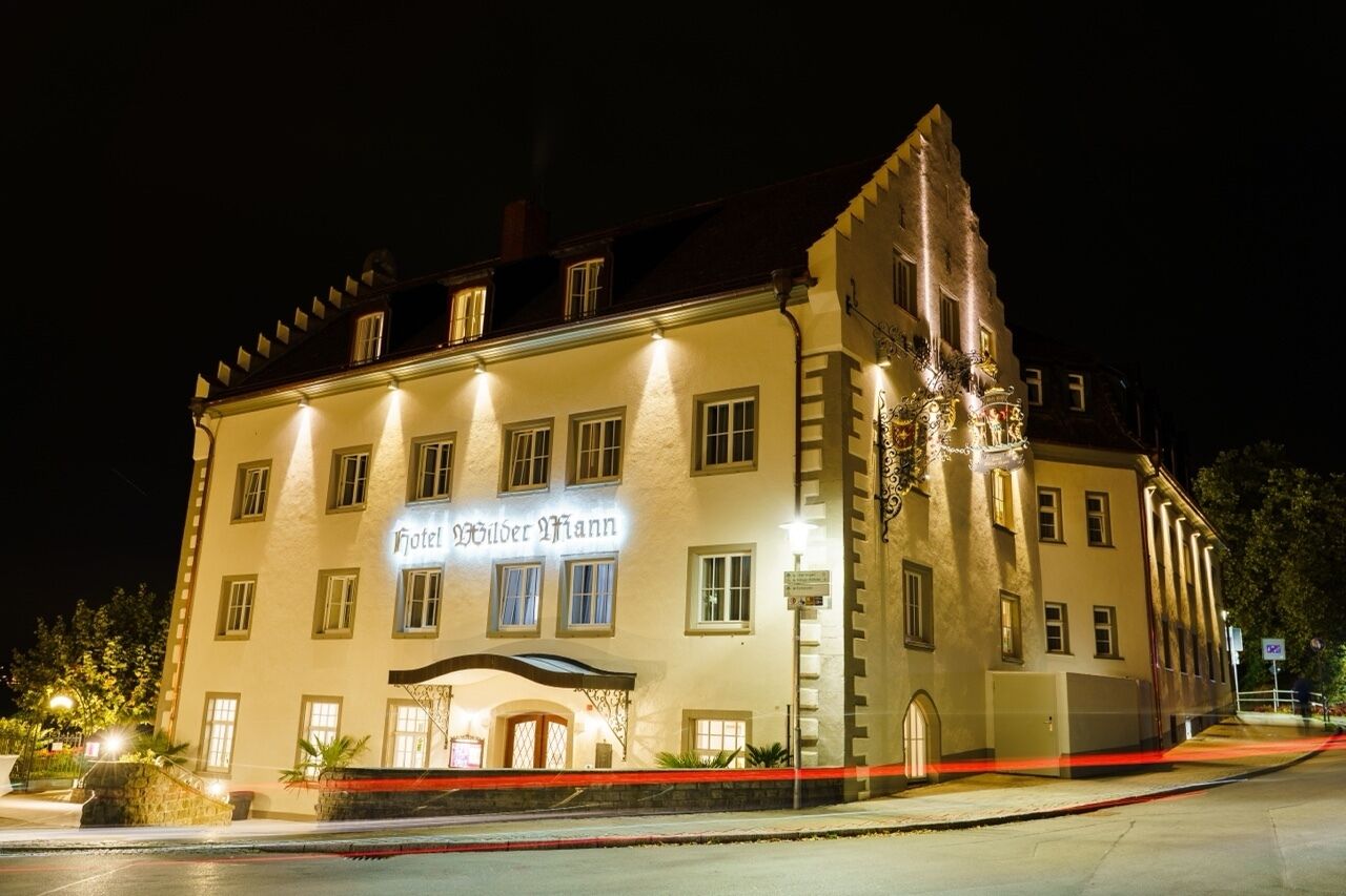 Un edificio histórico con un letrero que dice 'Hotel Wilder Mann' por la noche.