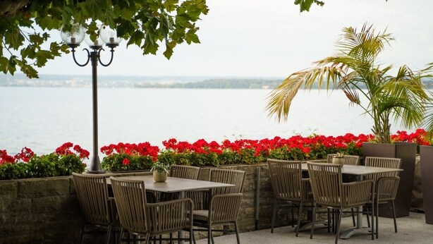 An outdoor patio with wicker furniture and a view of the water.