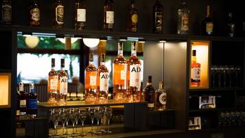 Un espace bar avec de nombreuses bouteilles d’alcool, dont une sélection bien visible de bouteilles de la marque « AIX », et plusieurs verres alignés sur le comptoir.