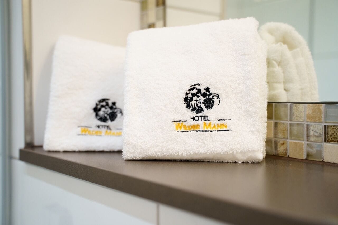 Two white towels with a logo and text on a countertop.