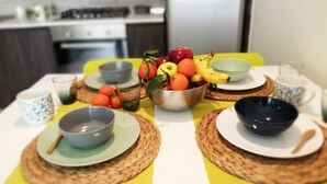 A dining table with a fruit bowl, bowls, and placemats.