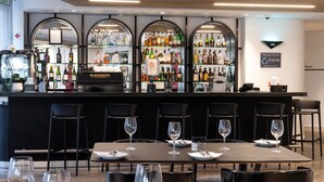 A bar area with multiple seating tables, each with a wine glass and cutlery. - ANEW Hotel Green Point (Cape Town)