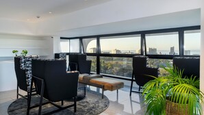 A modern living room with a large window, black and white patterned chairs, a bench, and a potted plant. - ANEW Hotel Green Point (Cape Town)