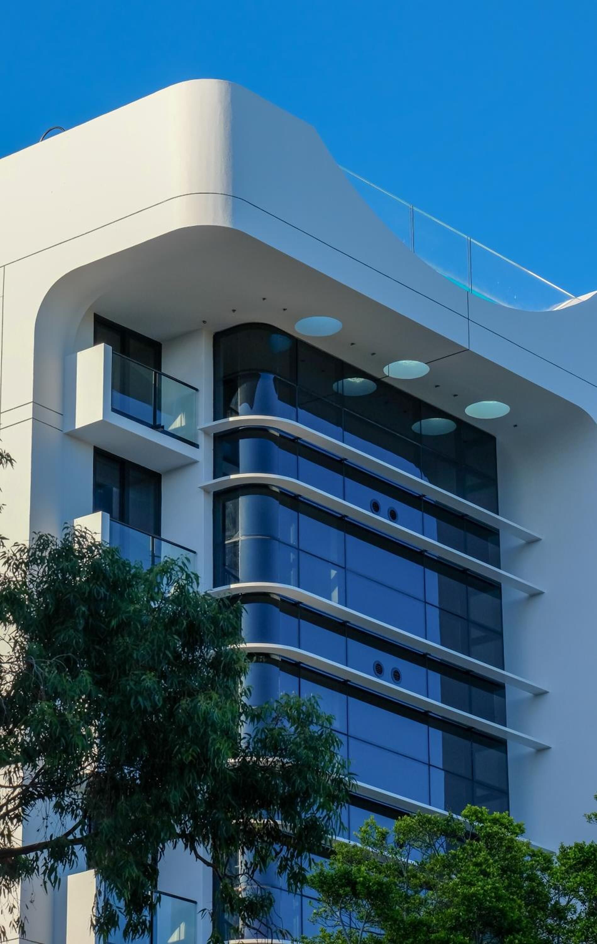 Un edificio moderno con fachada curva, ventanas amplias y un balcón.