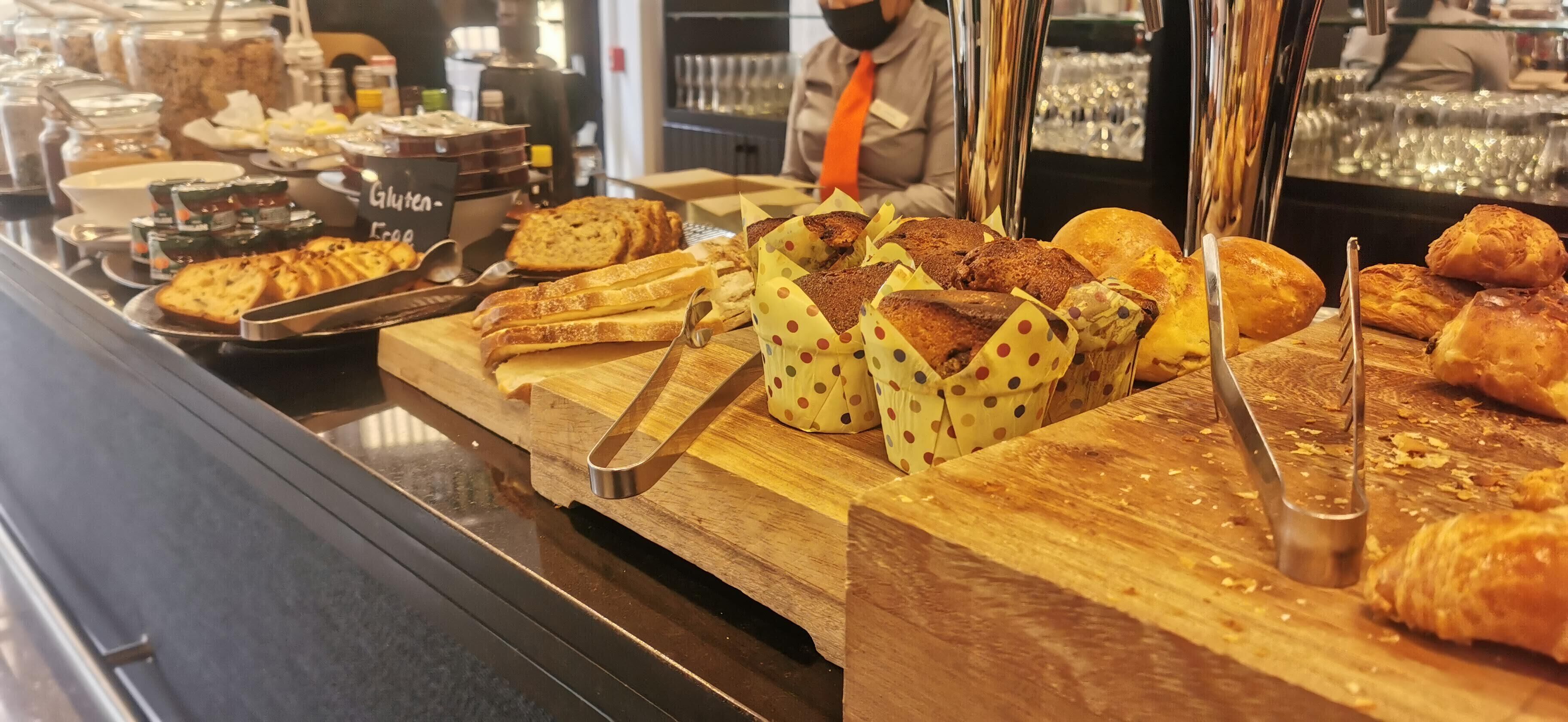 A breakfast buffet with various breads and pastries.