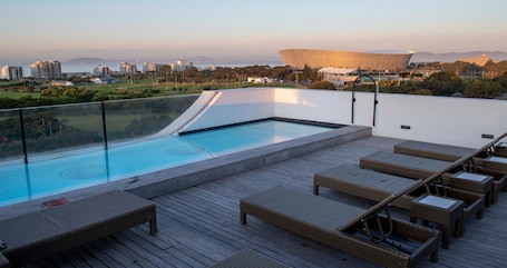 Una piscina al aire libre, sillones reclinables de piscina