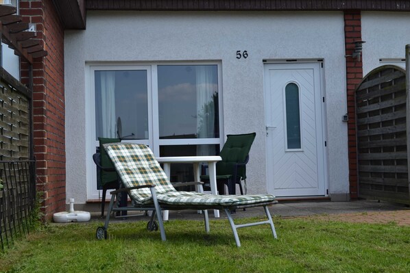 A house with a number 56 on the door, a white exterior, and a green lawn.
