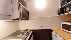 A compact kitchen with a stove, microwave, and sink.