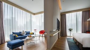 A modern hotel room with a sofa, ottoman, dining table, and a bed. - Holiday Inn Express Shenzhen Nanshan by IHG (Shenzhen)