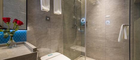 Un baño moderno con ducha acristalada, inodoro y zona de lavamanos con un florero.