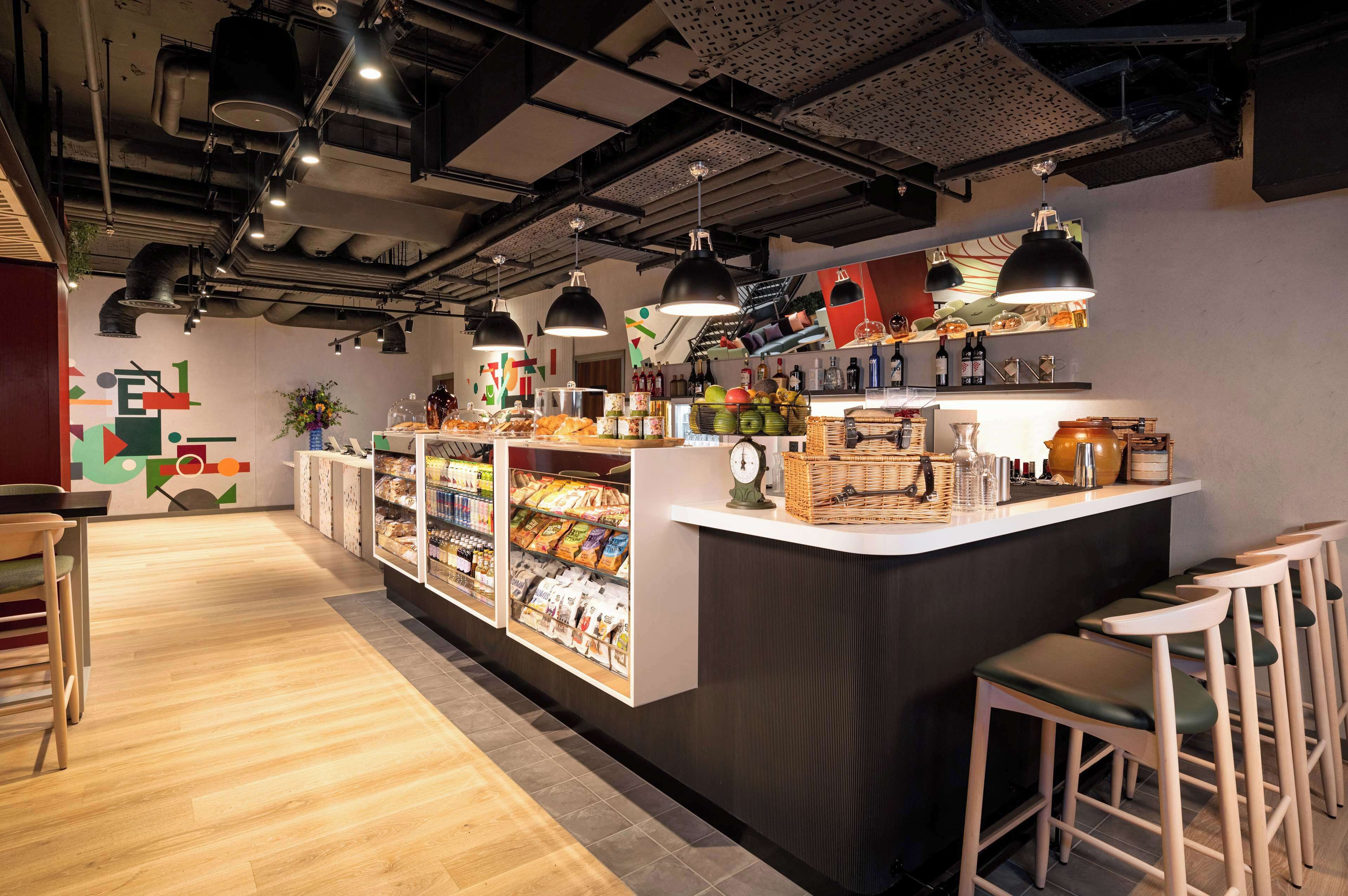 A modern cafe with a counter, seating area, and a variety of food items displayed.