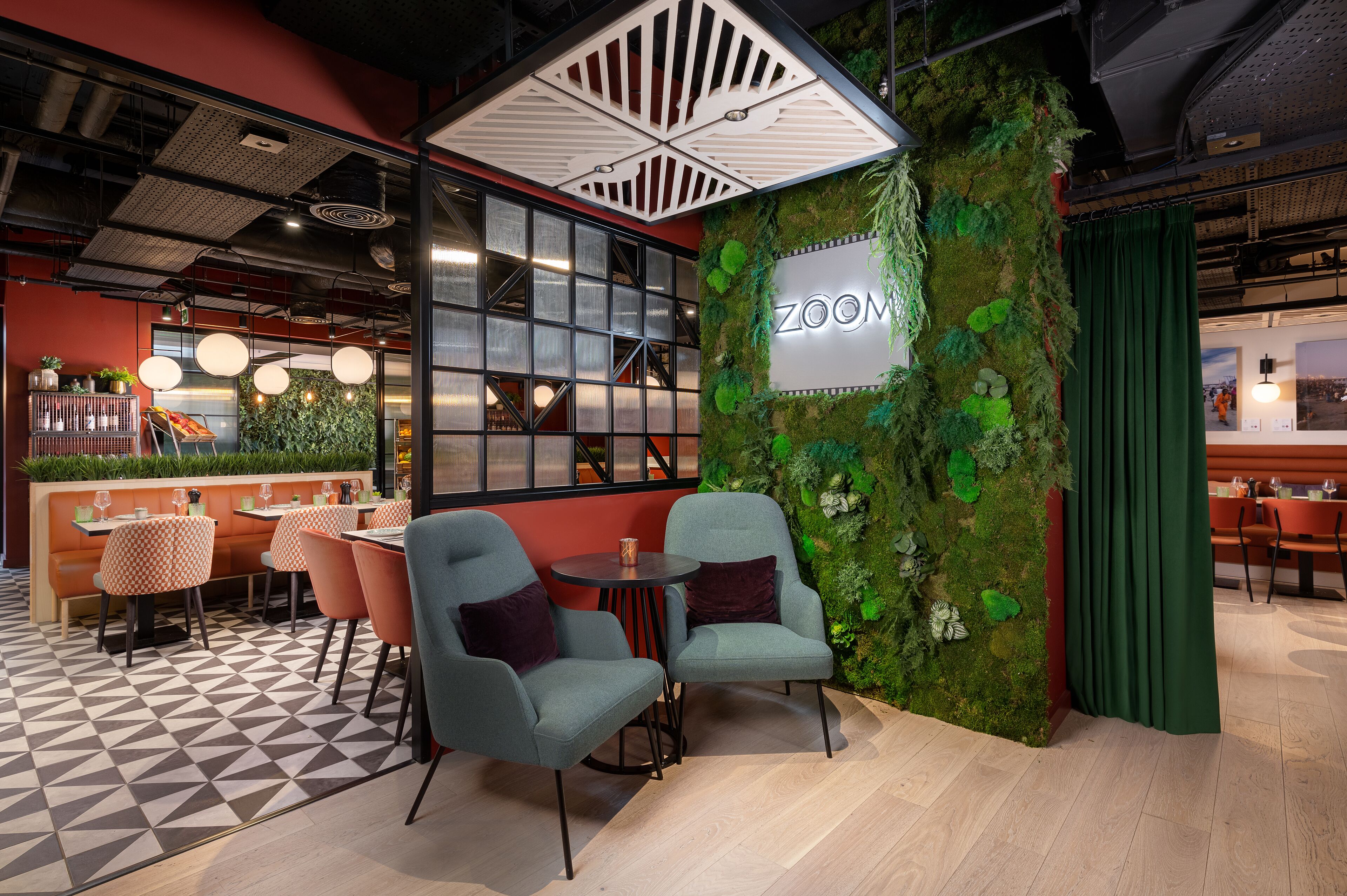A modern interior with a green wall, seating area, and a visible 'ZOOM' sign.