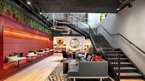 A modern lounge area with seating, a staircase, and a large mirror.