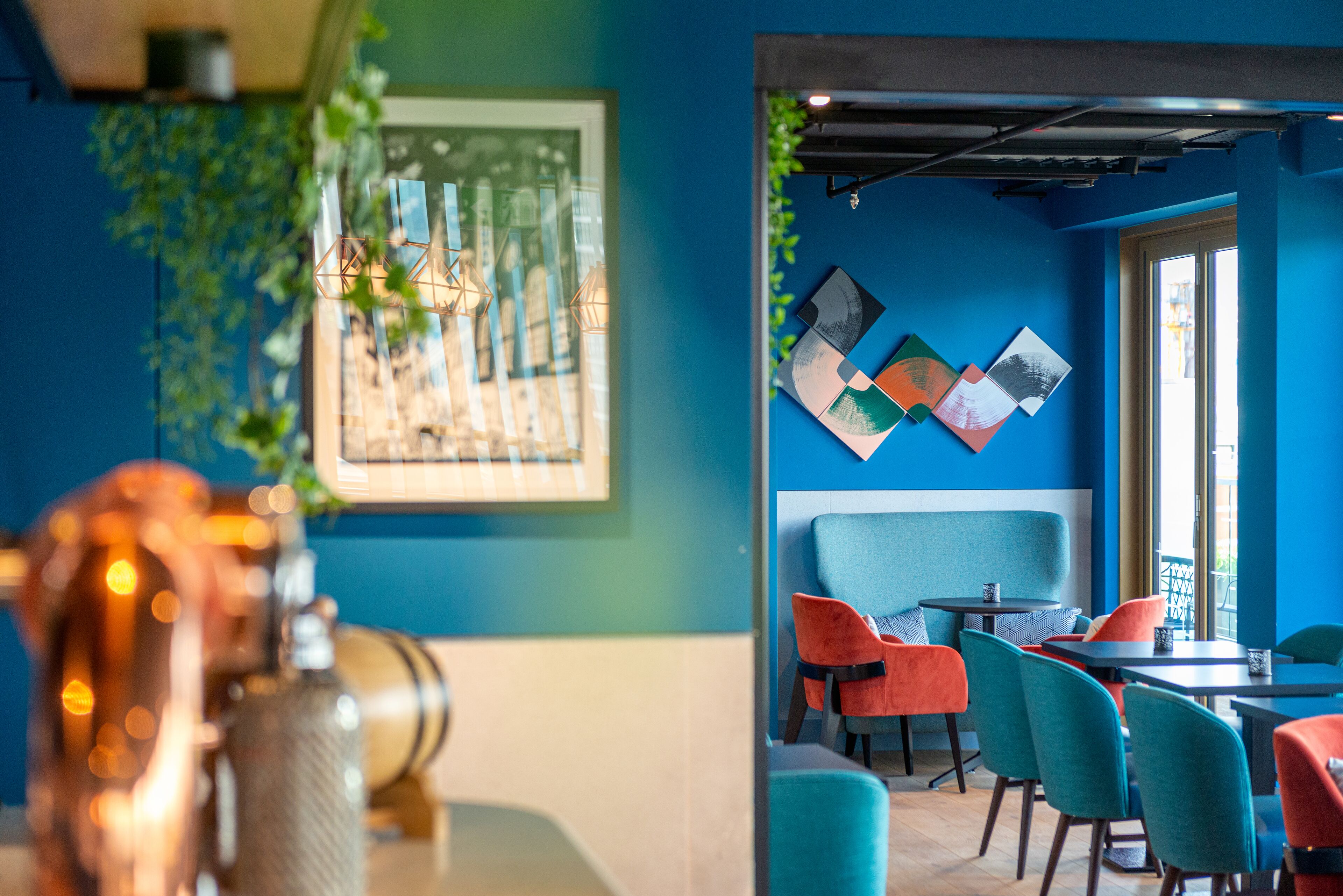 Un interior moderno con paredes verde mar, una zona de asientos tipo cabina en azul y sillas de colores.