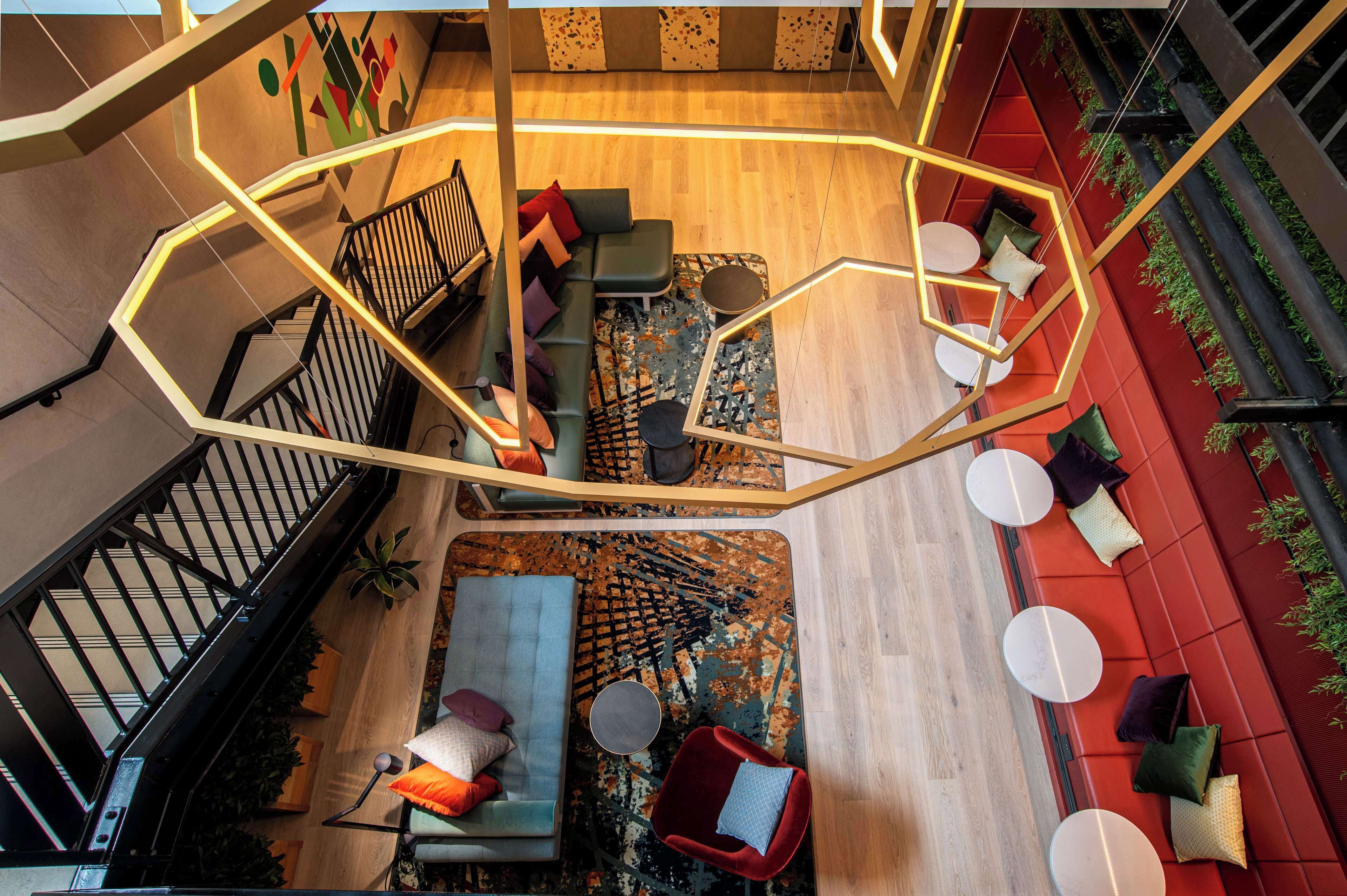 A modern interior with a staircase, seating areas, and a wooden floor.