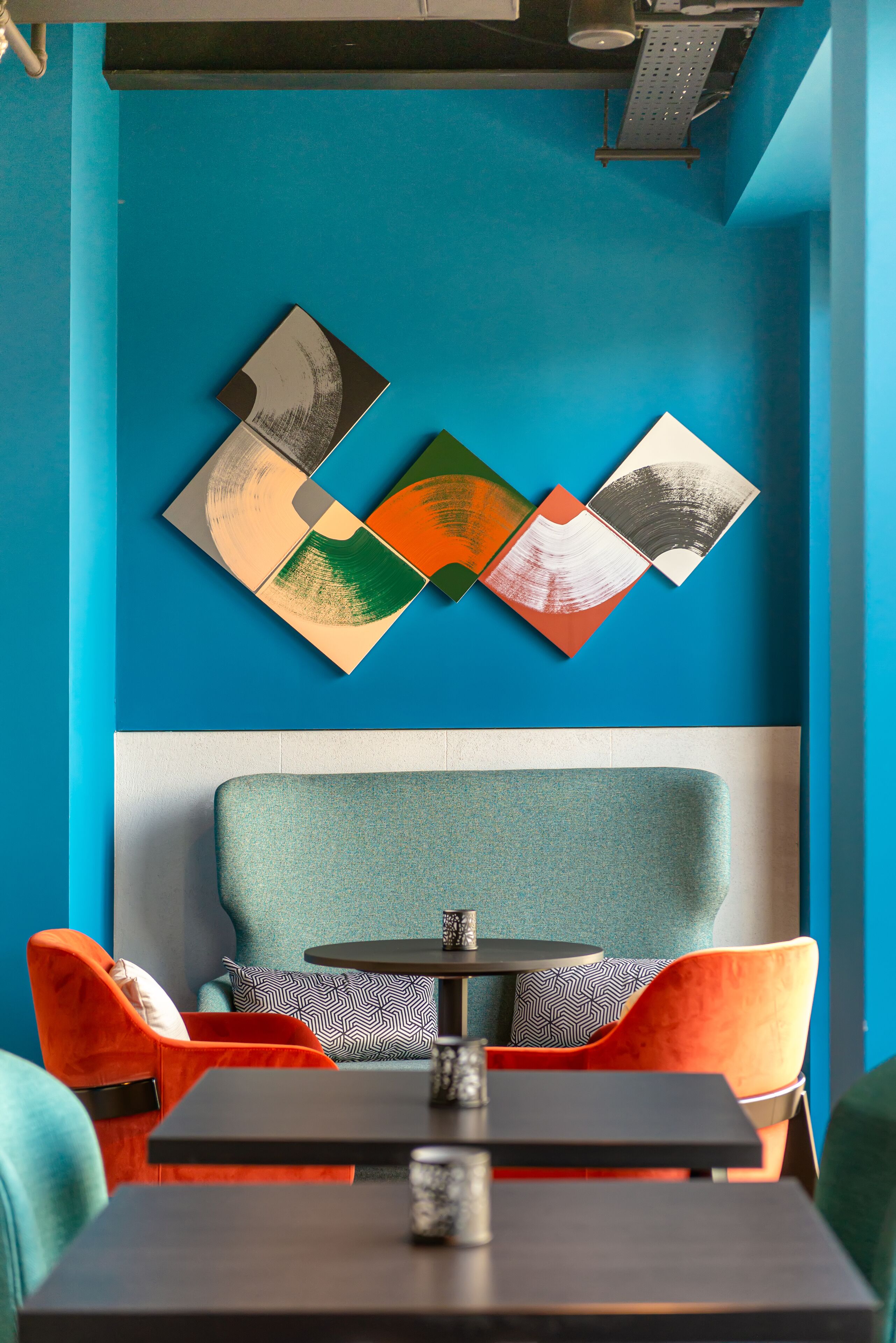 A modern interior with a blue wall, a sofa with patterned cushions, and a table with a coffee cup.