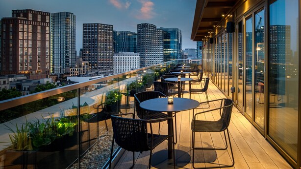 Terraza en la azotea con mobiliario exterior, vistas a la ciudad y arquitectura moderna.