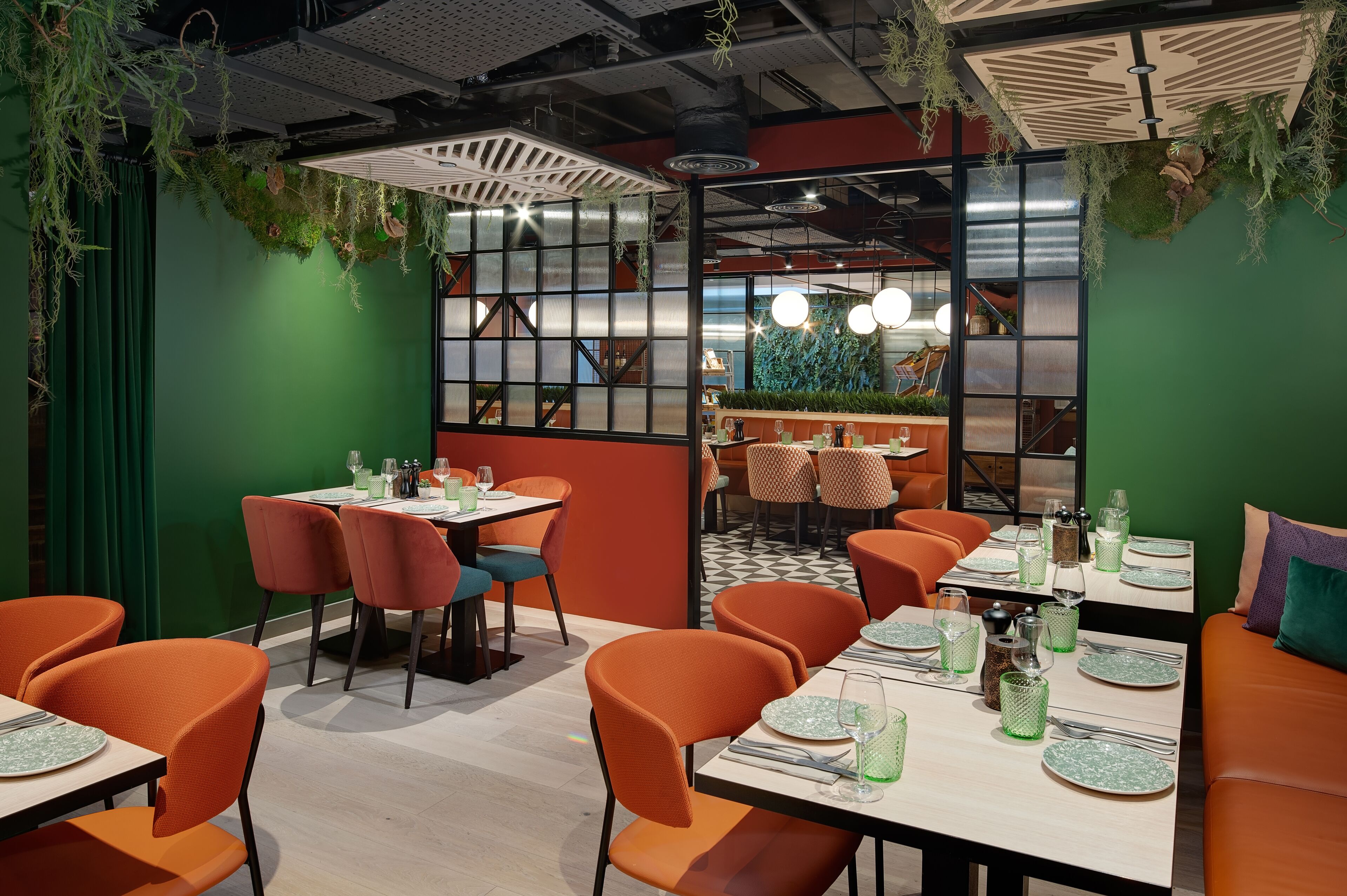 A restaurant with green walls, orange chairs, and tables set for dining.