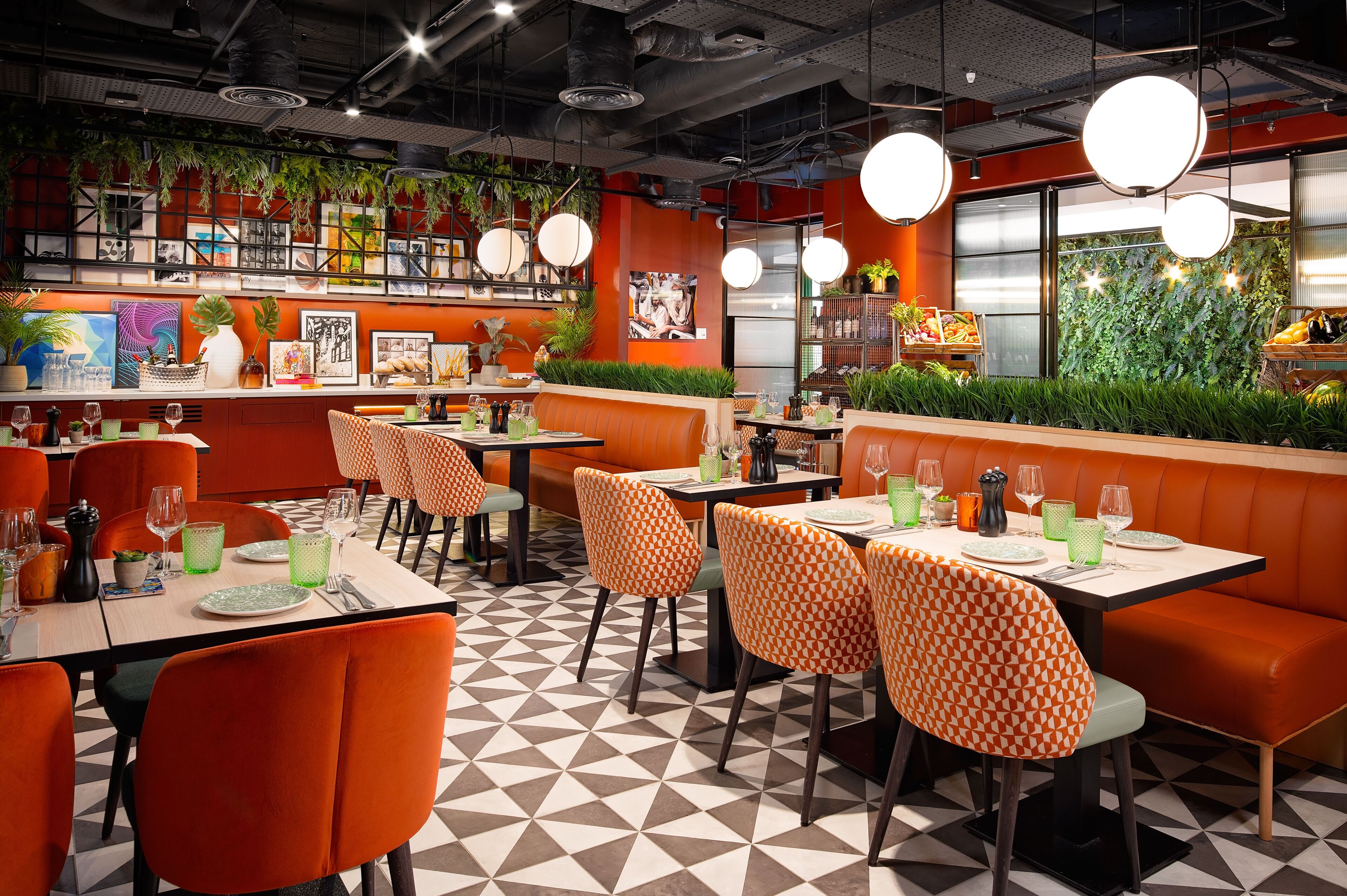 A restaurant with orange booths, tables, and a checkered floor.