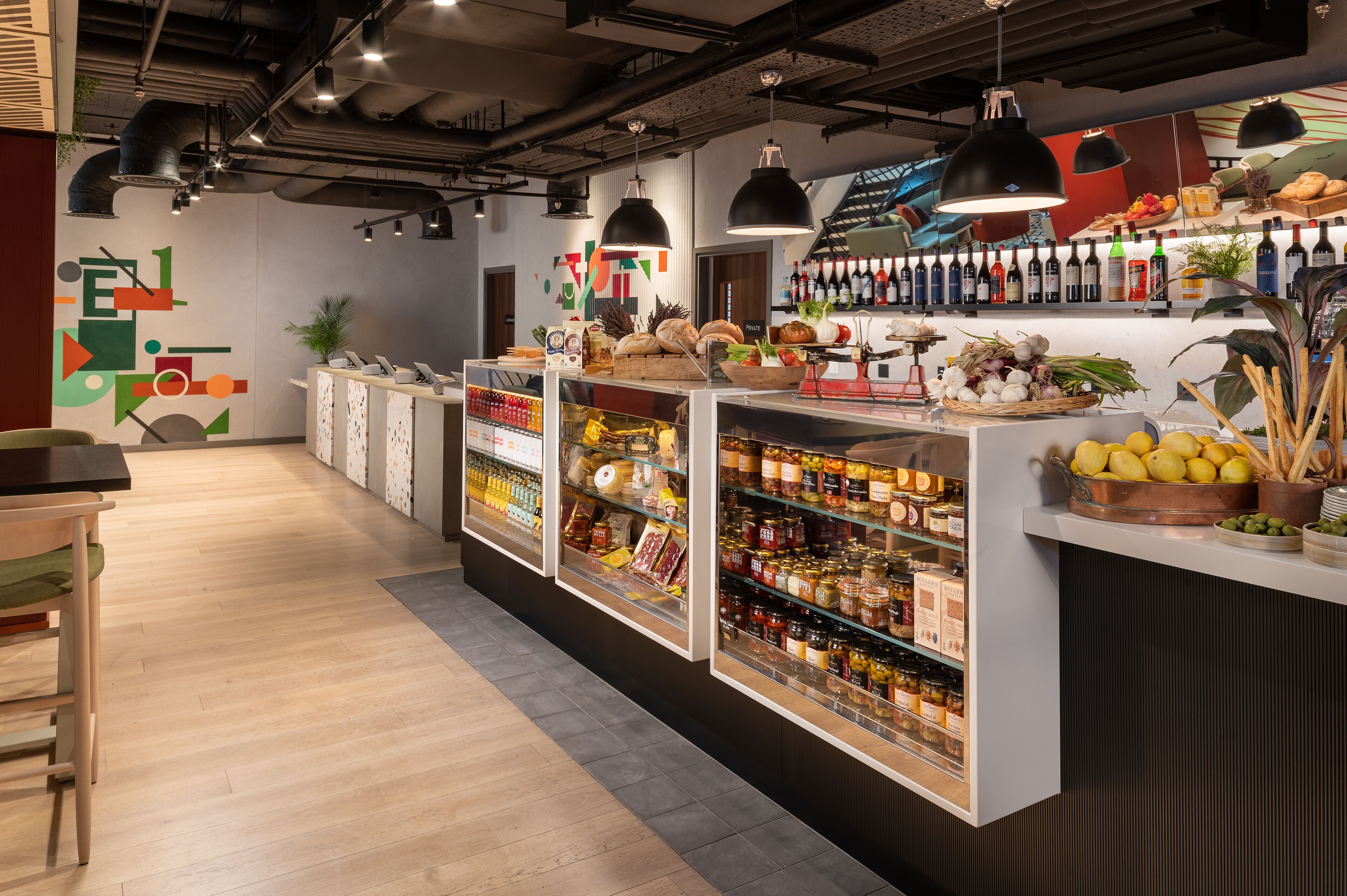 A modern interior with a long counter displaying various food items and condiments.