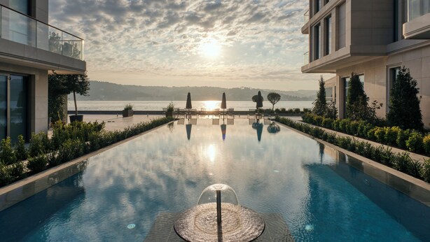 A serene pool area with a clear view of the sunset over the water, surrounded by modern buildings. - Mandarin Oriental Bosphorus, Istanbul (Istanbul)