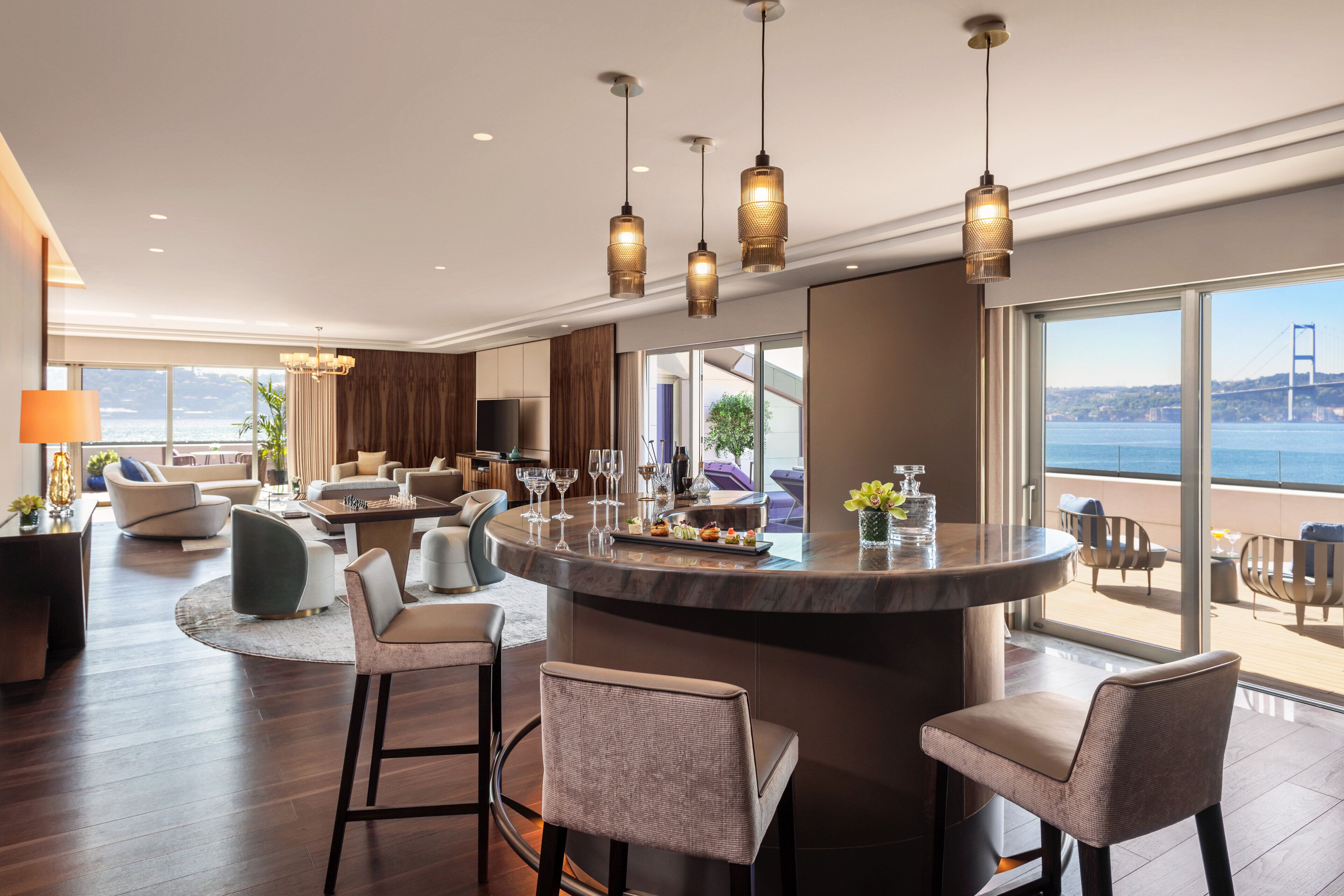 A modern interior with a bar area, seating, and a view of the sea.