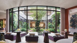 A modern hotel lobby with a curved glass wall, seating areas, and a view of a lush garden. - Mandarin Oriental Bosphorus, Istanbul (Istanbul)