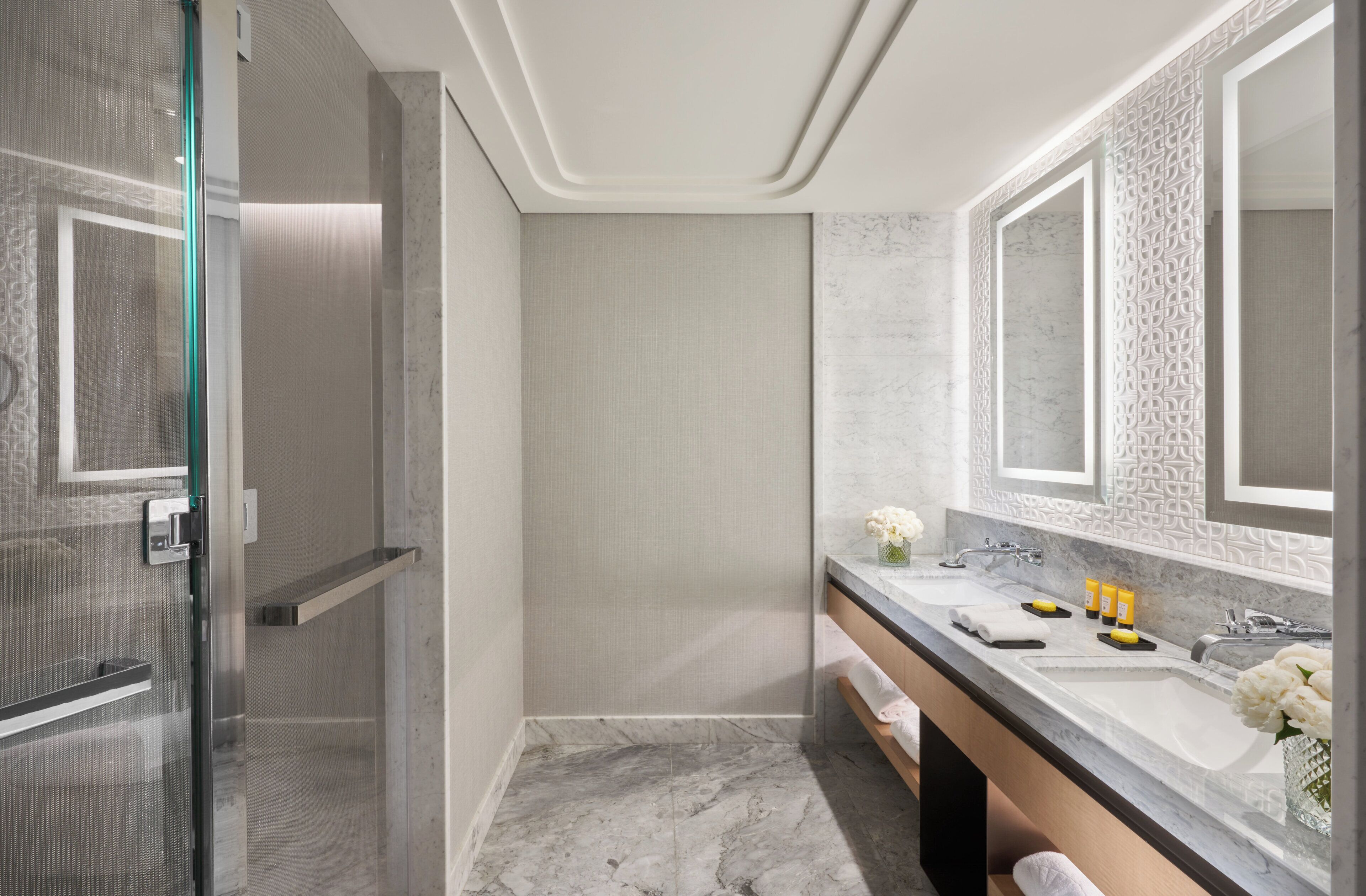 Ein modernes Badezimmer mit barrierefreier Dusche, einem großen Spiegel und einem Waschtisch mit zwei Becken.