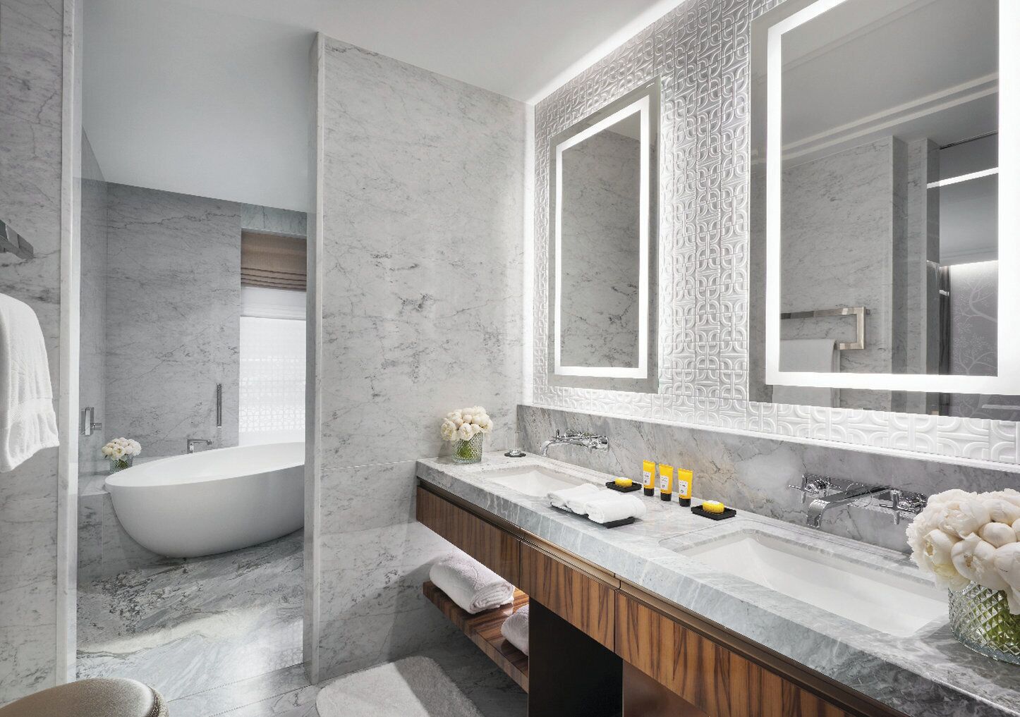 Ein modernes Badezimmer mit einer freistehenden Badewanne, einem großen Spiegel und einem Waschtisch mit Marmorplatte.