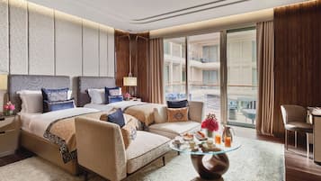 A hotel room with two beds, a sofa, a glass coffee table, and a view of the outside balcony.