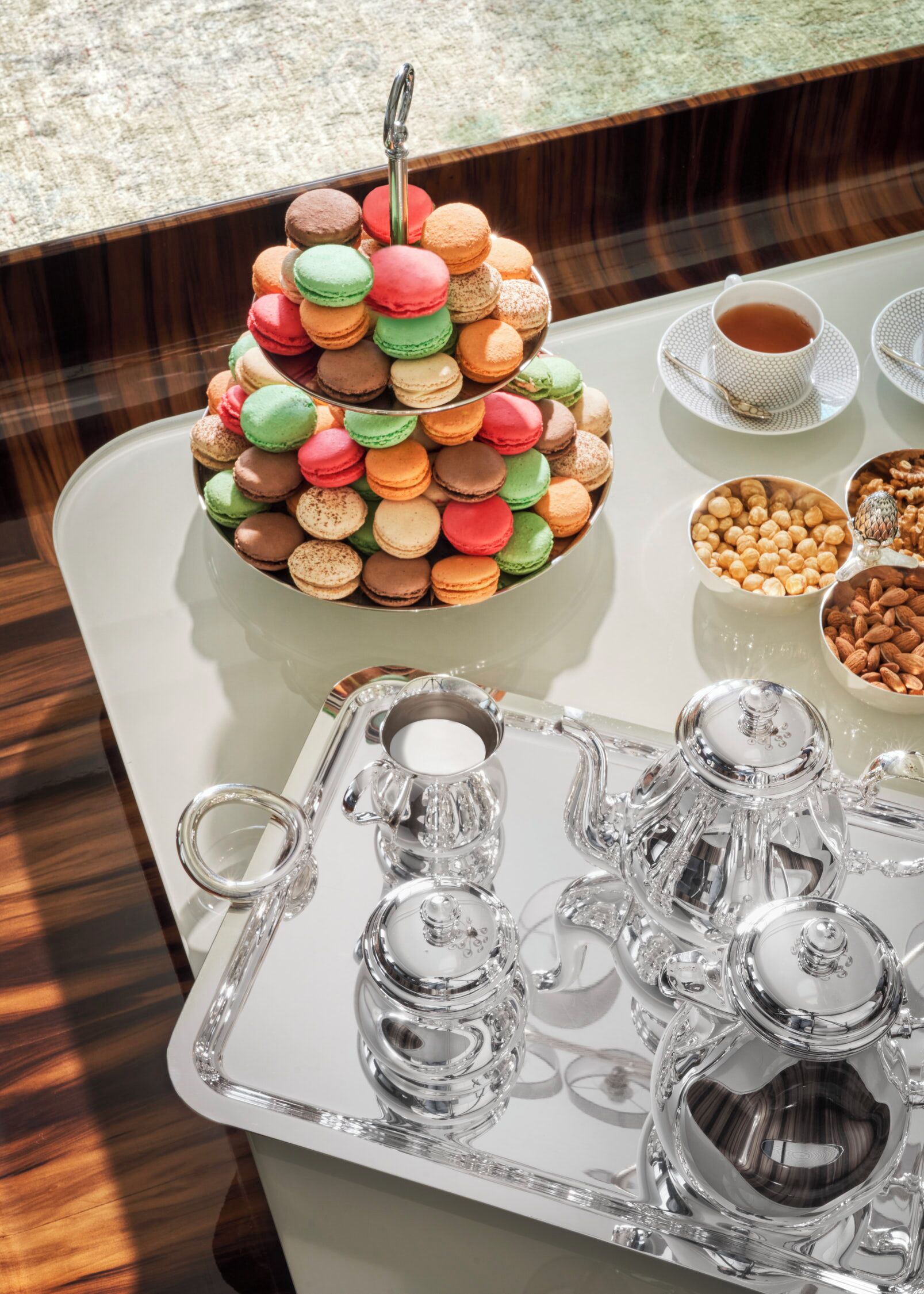 A tray with a tiered macaroon display, a teapot, and a cup of tea.
