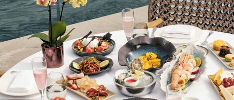 A table set for a meal with various dishes, a drink, and a view of the water.