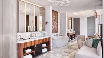 Ein modernes Badezimmer mit freistehender Badewanne, einem großen Spiegel und einem Marmorboden.