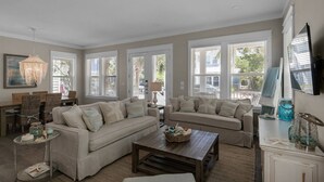 A spacious living room with a sectional sofa, a coffee table, and a dining area with wicker chairs.