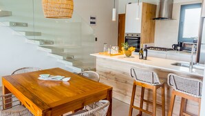 A modern kitchen with a central island, stainless steel appliances, and a glass staircase. - Elegant and spacious Penthouse with View (Punta Cana)