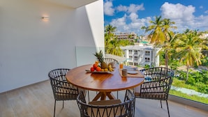 A balcony with a wooden table, chairs, and a fruit bowl. - Elegant and spacious Penthouse with View (Punta Cana)