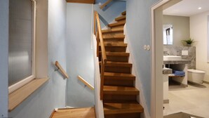 A wooden staircase with a handrail, leading to a bathroom with a sink and toilet. - Gemütliches Stadthaus im Herzen der Altstadt (Bad Dürkheim)