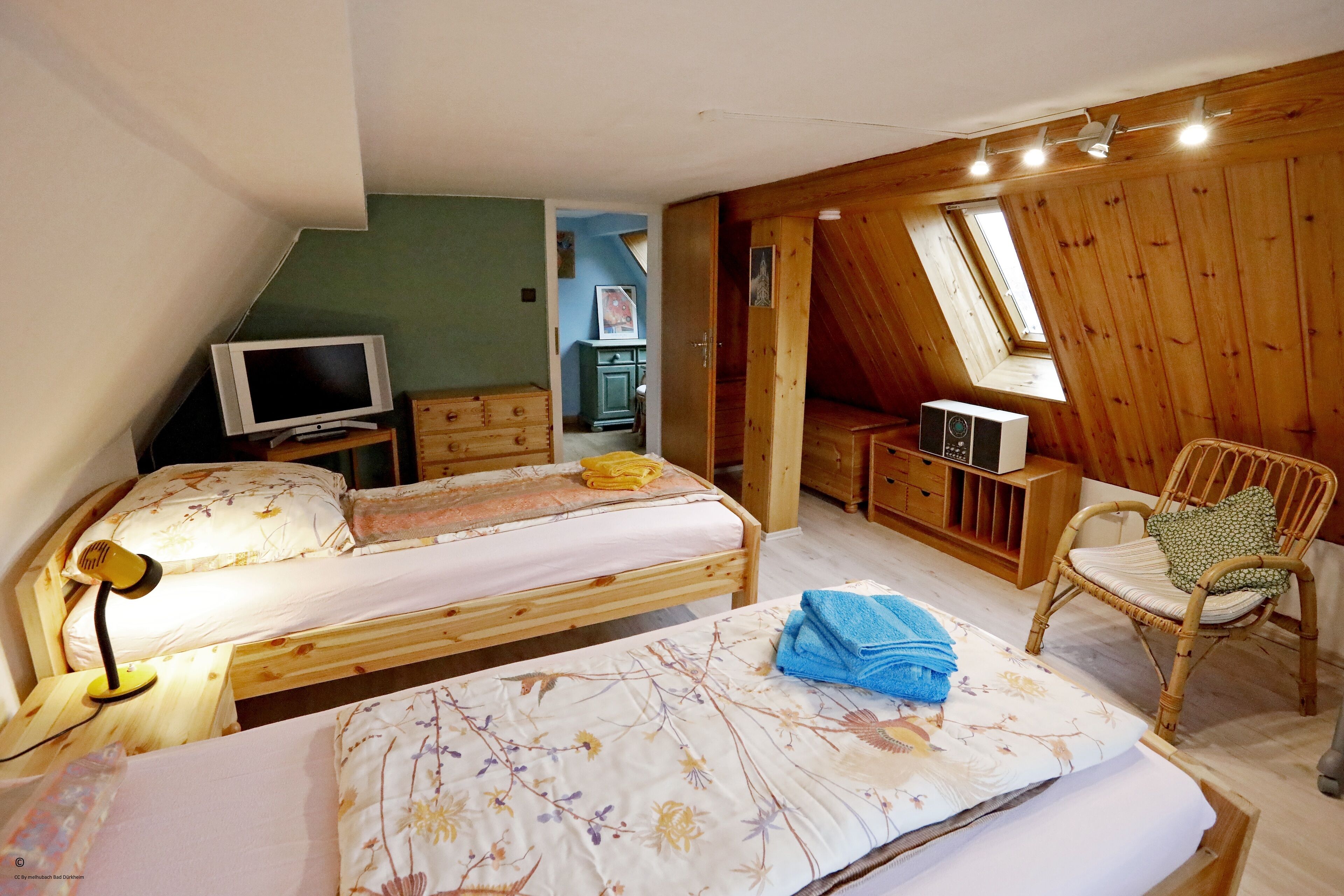 Un dormitorio con dos camas, un televisor, un escritorio con una radio y una silla.