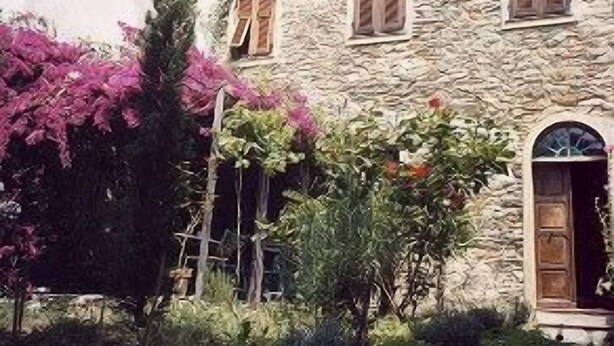 Un edificio de piedra con contraventanas y puerta de madera.